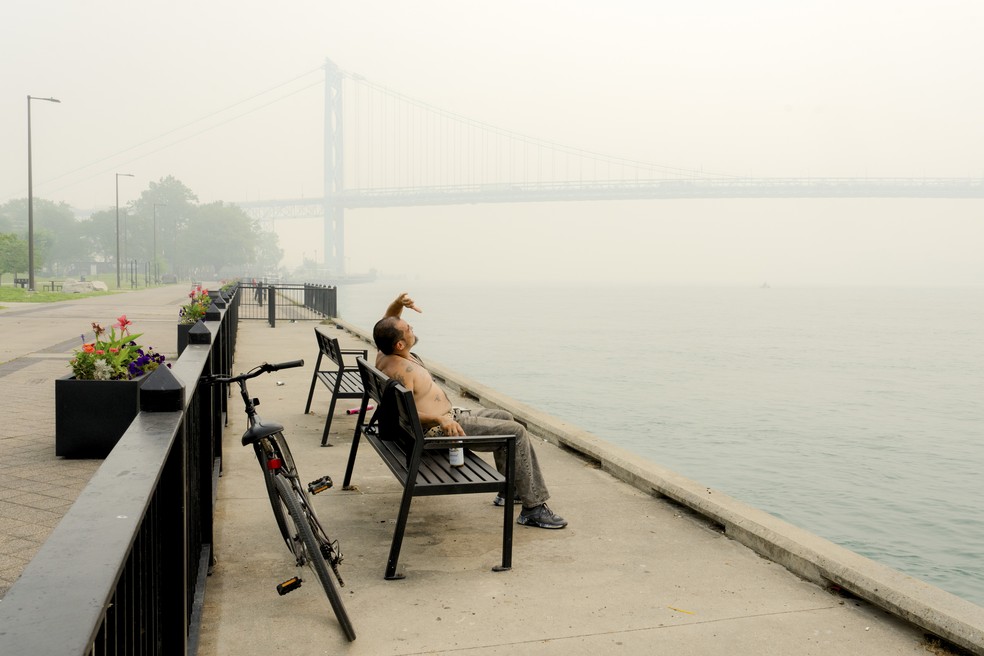 Um homem olha para o céu tomado pela fumaça dos incêndios florestais no Canadá, às margens do Rio Detroit, próximo à Ponte Ambassador, que liga os Estados Unidos ao Canadá, em Detroit, na quinta-feira, 16 de julho de 2026. A qualidade do ar em várias cidades atingiu níveis perigosos na manhã de quinta-feira, enquanto a fumaça deve se deslocar por toda a América do Norte — Foto: Nic Antaya/The New York Times