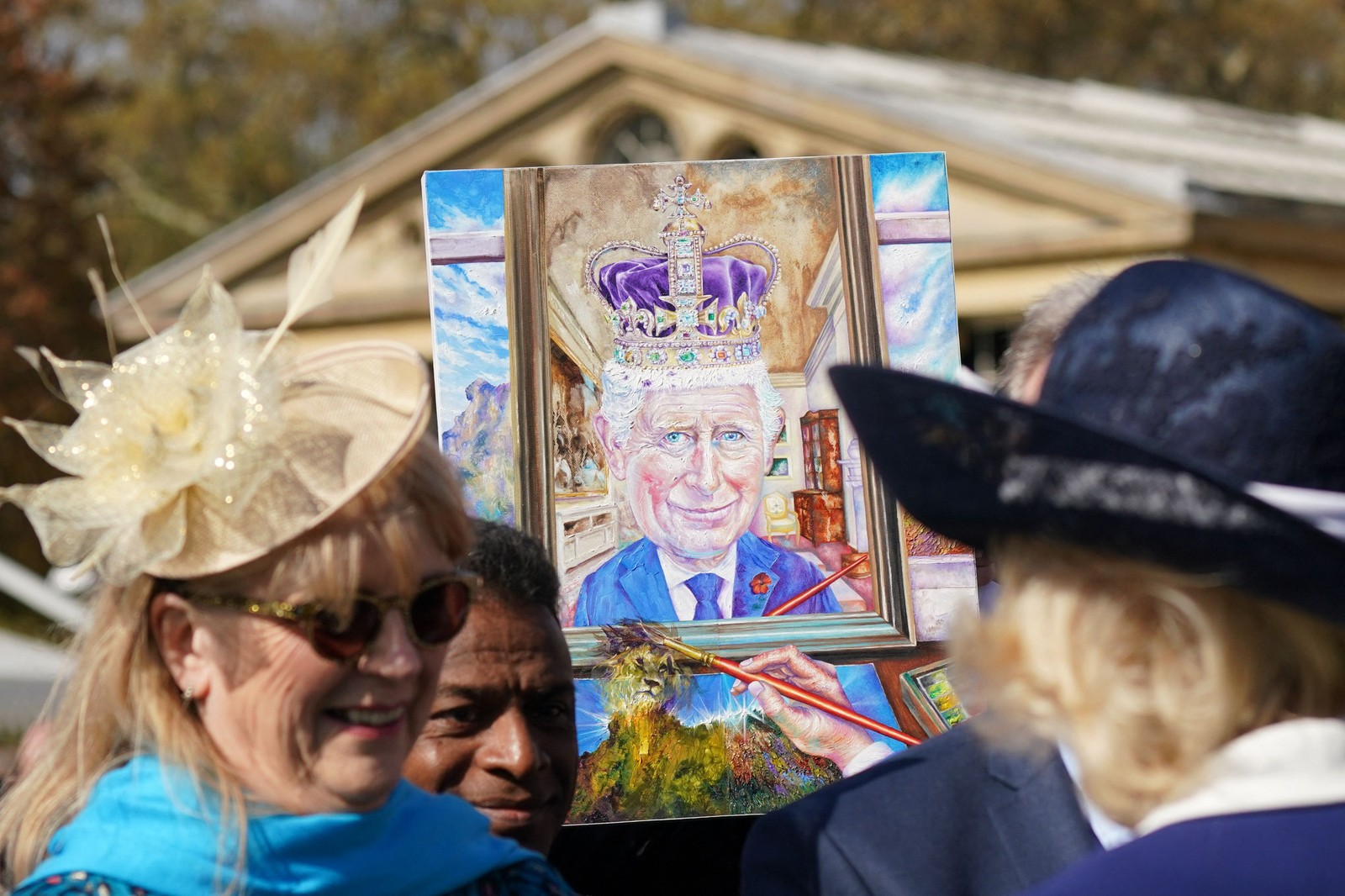 Convidado segura uma pintura representando o rei Charles III, no Palácio de Buckingham, em Londres — Foto: Yui Mok / POOL / AFP