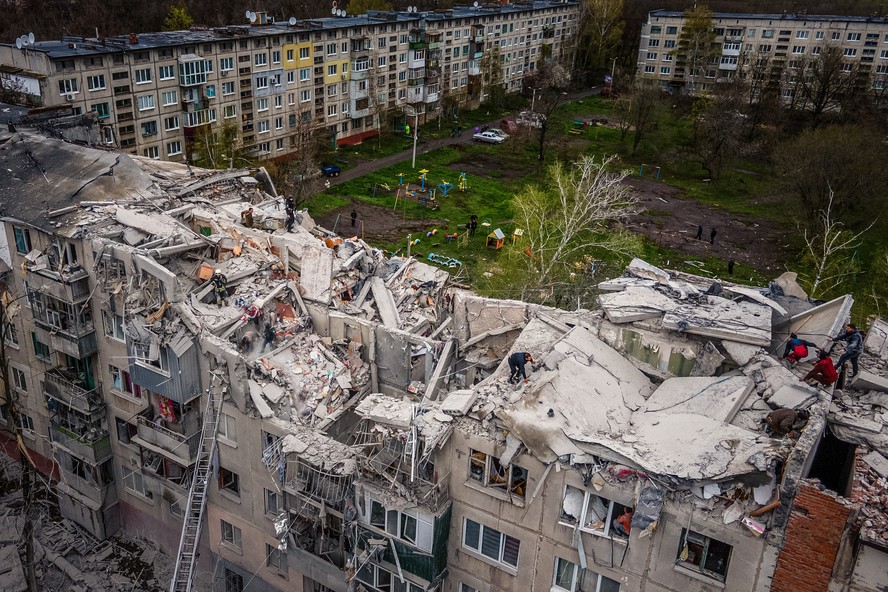 Vista aérea mostra equipes de resgate no topo de um prédio residencial parcialmente destruído, após um bombardeio em Sloviansk, na Ucrânia