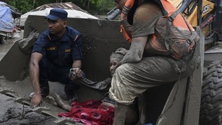 Equipes de resgate usam uma escavadeira para transportar uma pessoa afetada por inundações repentinas em Devghat, no distrito de Nuwakot, no Nepal, em 26 de agosto de 2026 — Foto: Prakash MATHEMA / AFP
