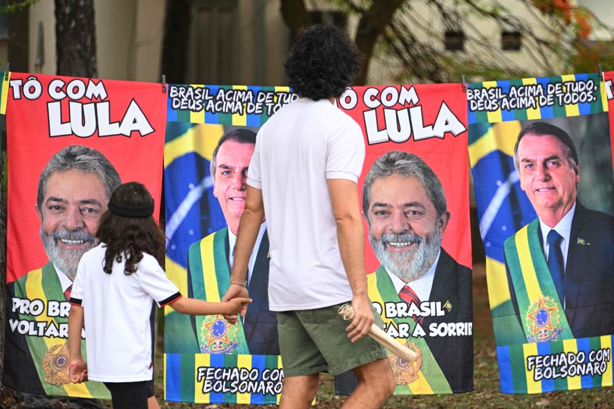 Pedestres passam por toalhas à venda com imagens de Lula e Bolsonaro em via de Brasília