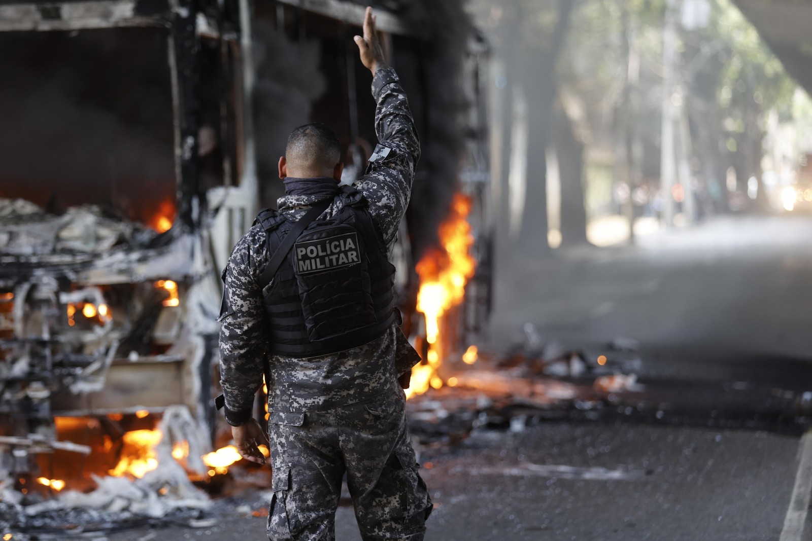 Policial militar acompanha o incêndio a um ônibus na Avenida Paulo de Frontin, no Rio Comprido — Foto: Gabriel de Paiva/ Agência O Globo
