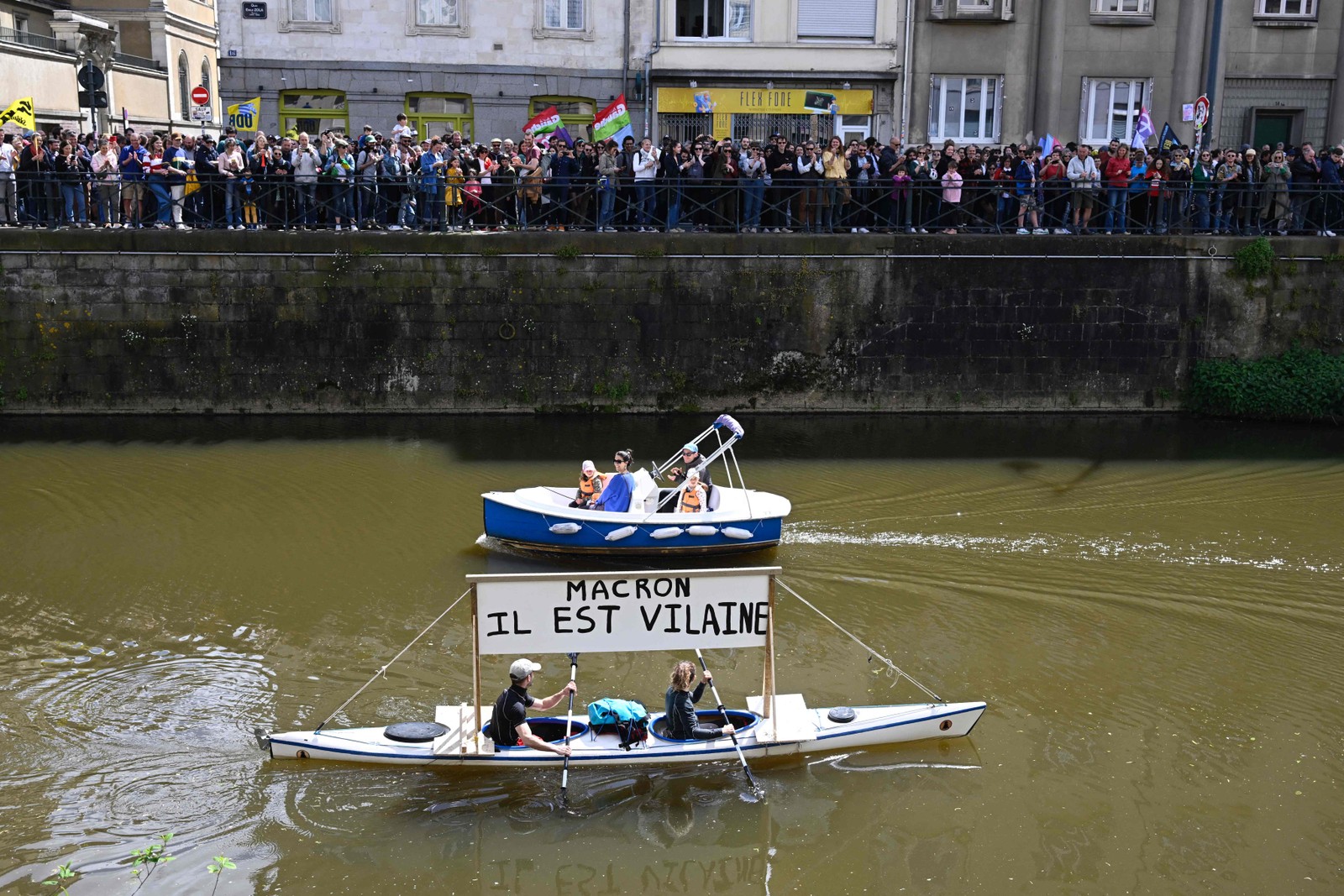 Manifestantes remam uma canoa com um cartaz que diz "Macron, ele é um vilão" — Foto: Damien MEYER / AFP