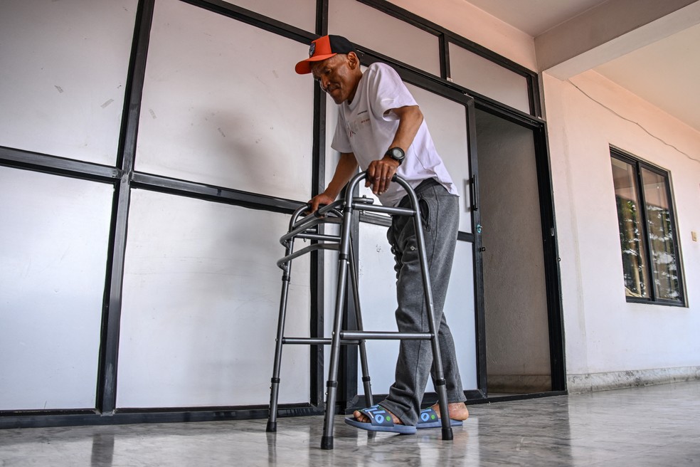 Sobrevivente do Everest, Dawa Sherpa, caminha com apoio durante sua recuperação em Katmandu; montanhista nepalês passou seis dias no monte de características severas — Foto: Prakash Mathema / AFP