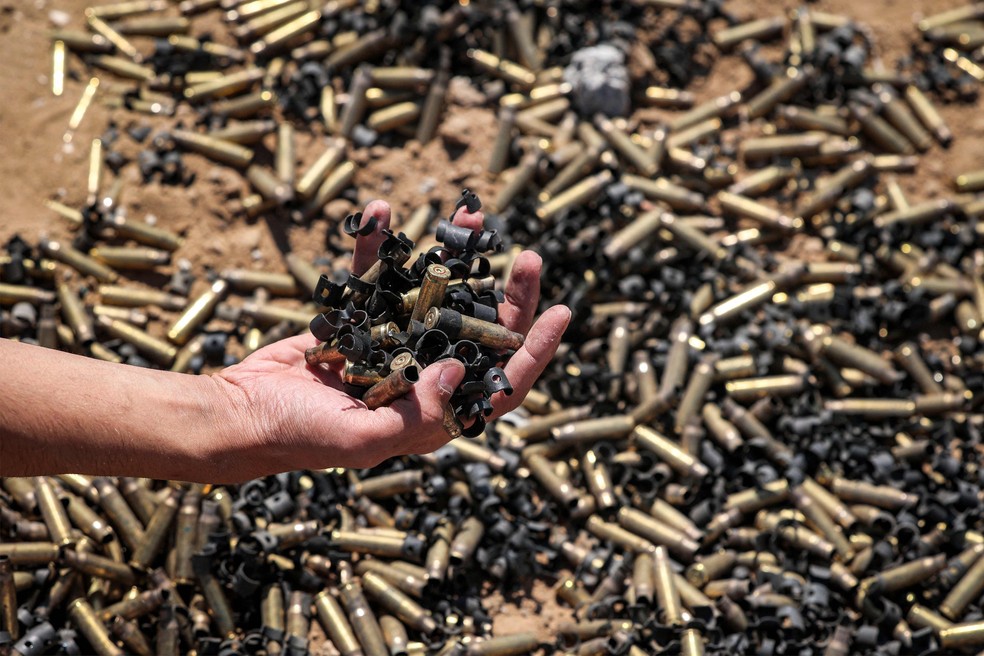Pessoa segura cápsulas de munição em Khan Yunis, na Faixa de Gaza, após retirada temporária das tropas israelenses da área — Foto: AFP
