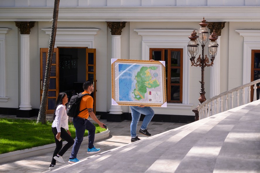 Funcionário da Assembleia Nacional carrega mapa com o território de Essequibo incorporado à Venezuela, antes de sessão parlamentar em Caracas