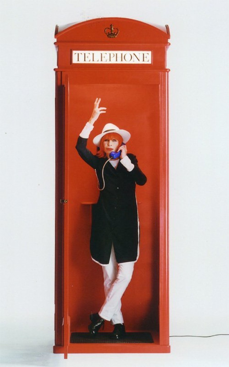 A cantora Rita Lee posa diante de um típico telefone britânico