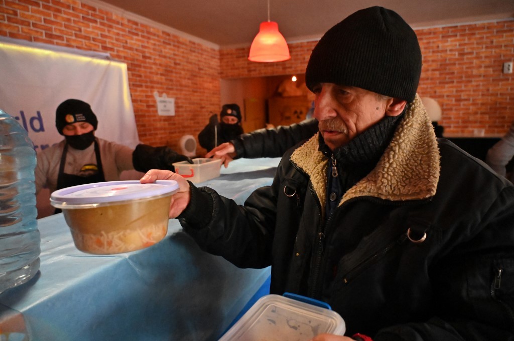 Um morador pega uma refeição distribuída por voluntários em Kupiansk, região de Kharkiv — Foto: SERGEY BOBOK / AFP - 13/02/2023