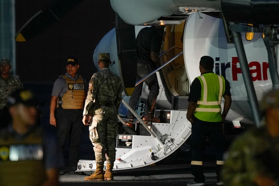 Um migrante colombiano, com as mãos e os pés algemados, sobe em um avião no aeroporto Albrook Gelabert, na Cidade do Panamá, em 20 de agosto de 2024, durante sua deportação
