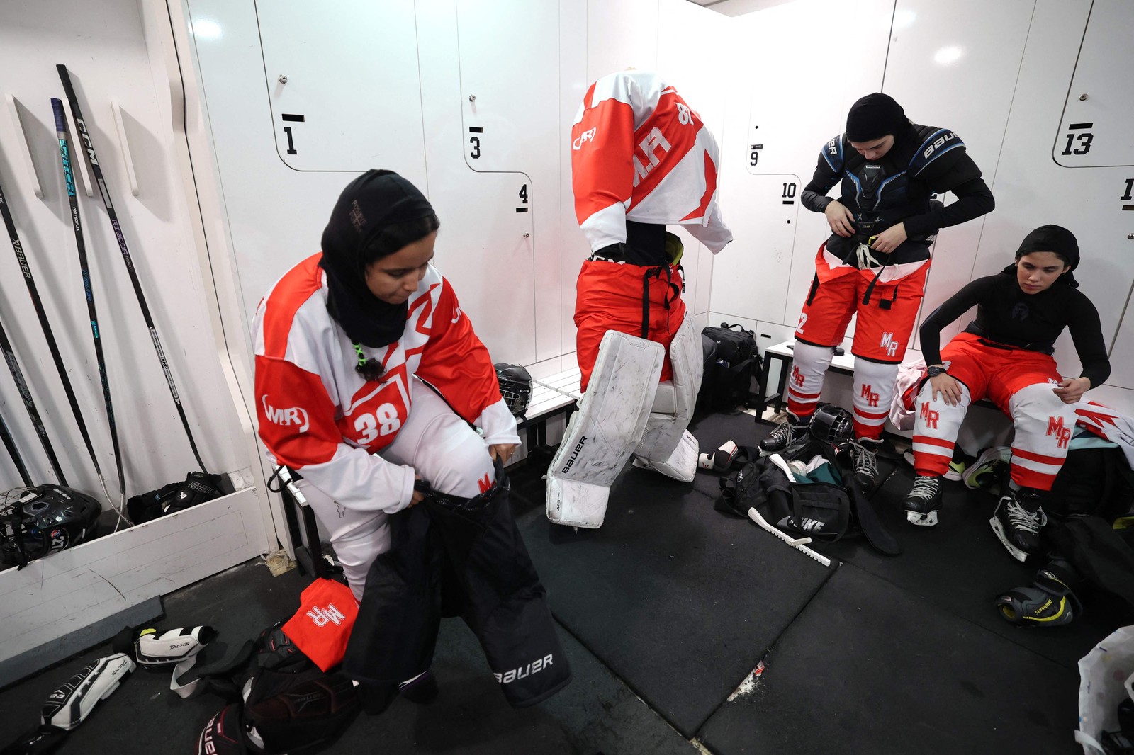 Jogadoras de hóquei escondem os cabelos sob um hijab e usam um capacete para proteger a cabeça dos golpes — Foto: Atta Kenare/AFP
