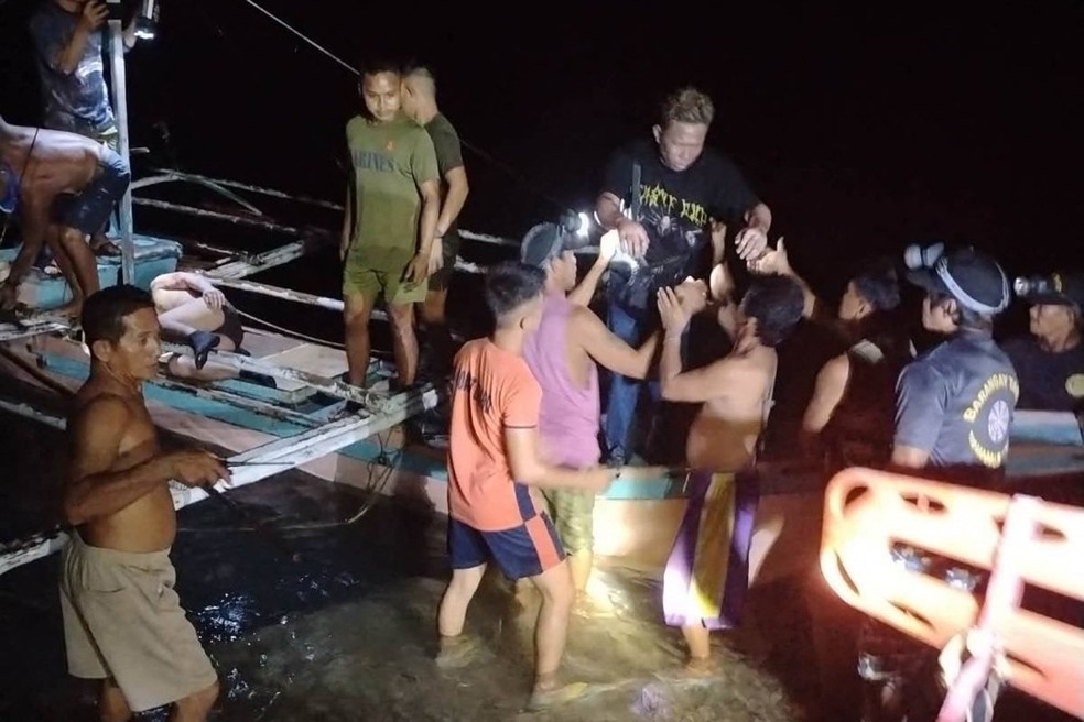 Pescadores volunt&aacute;rios auxiliam  sobreviventes de balsa que pegou fogo na costa de Palawan &mdash; Foto: PHILIPPINE COAST GUARD (PCG) / AFP