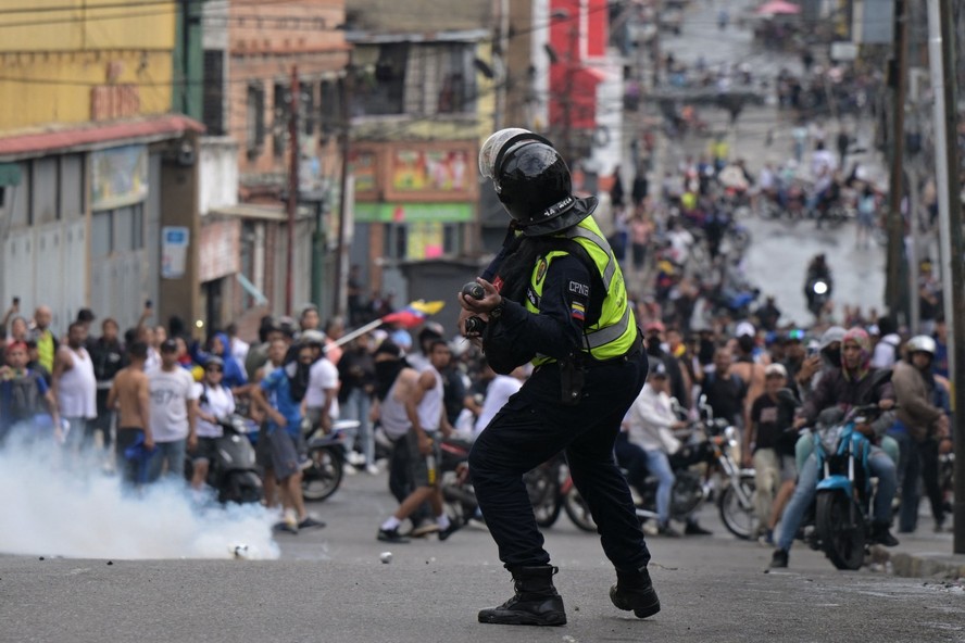 Policial joga bomba de g&aacute;s lacrimog&ecirc;neo contra manifestantes na Venezuela