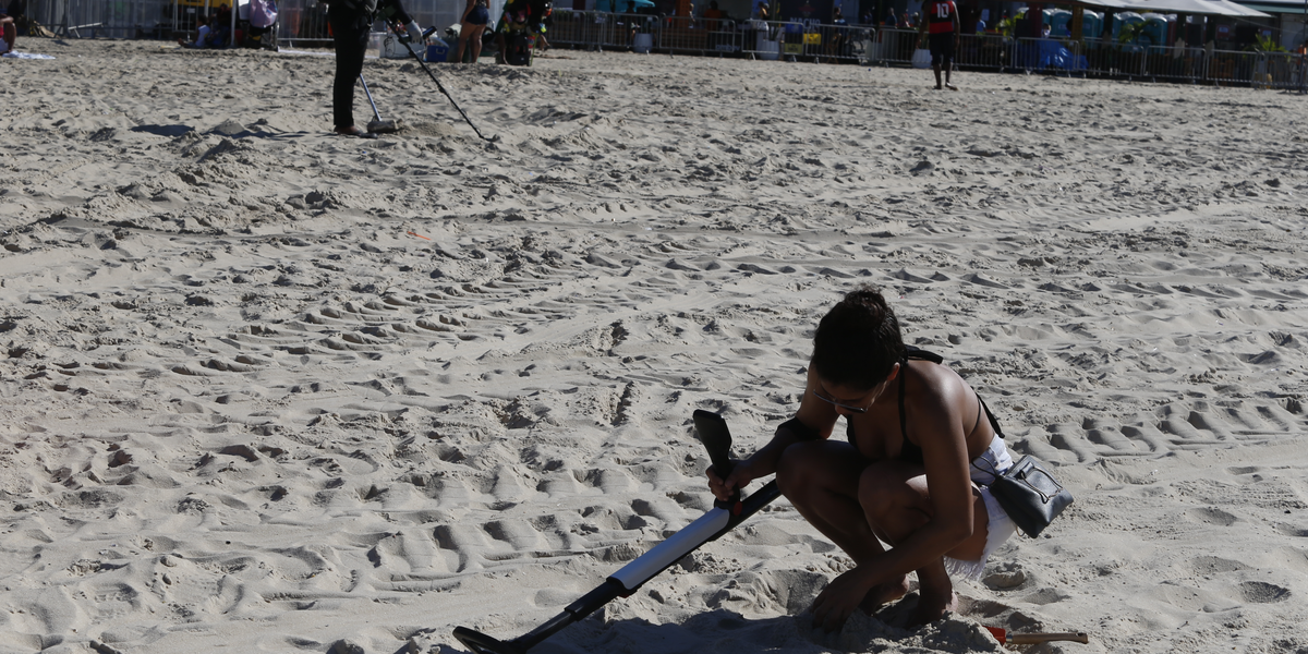 Em busca de tesouros: caçadores de metais garimpam Praia de Copacabana