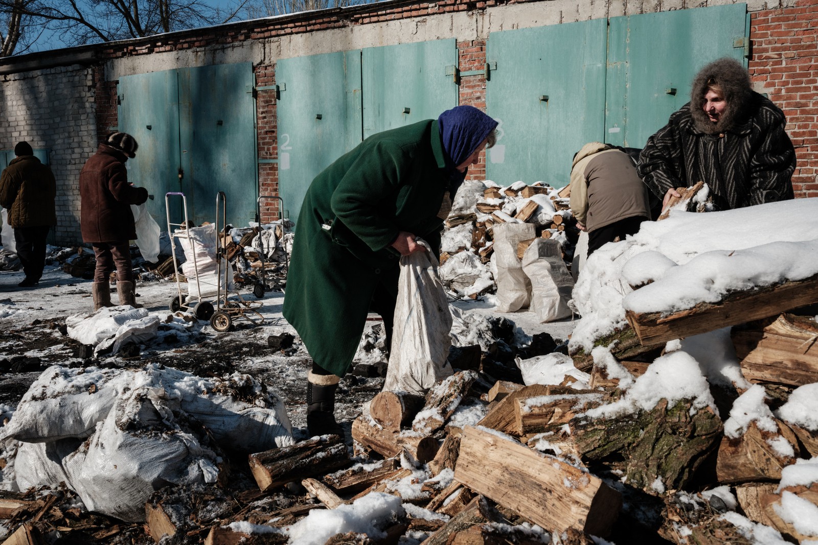 Lyubov Stepanova, de 71 anos, que mora no porão de seu apartamento com cerca de vinte outras pessoas, coleta lenha para cozinhar e se aquecer  — Foto: YASUYOSHI CHIBA / AFP