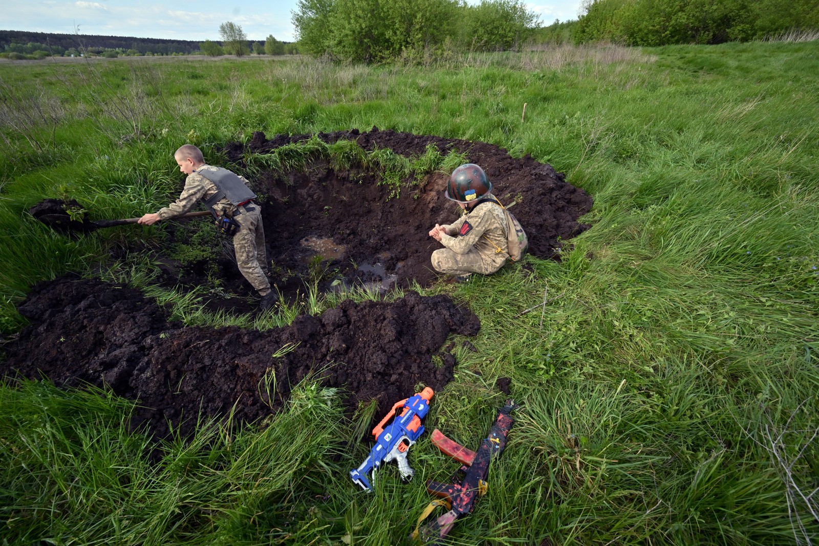 Crianças 'brincam' como se estivessem em trincheira da guerra na Ucrânia - Foto: Sergei Supinsky/AFP