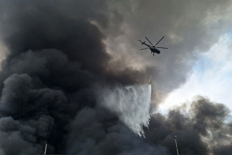 Helicóptero joga água em área do porto de Shahid Rajaee, no Irã, atingido por explosão e incêndio — Foto: Meysam Mirsadeh / TASNIM NEWS / AFP