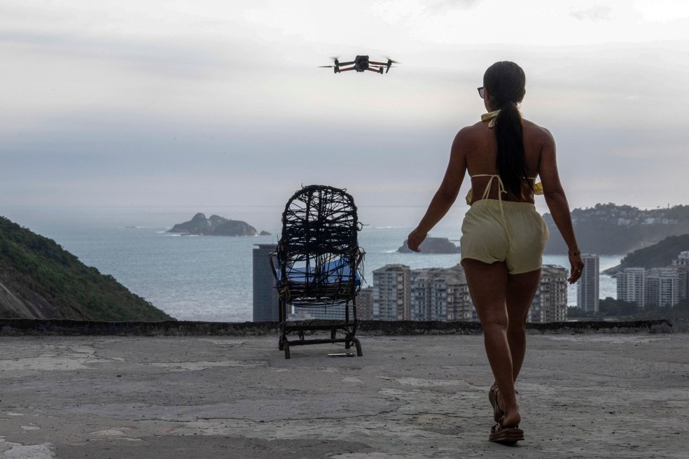 Uma mulher é filmada por um drone para um vídeo nas redes sociais no famoso mirante turístico “Porta do Céu”, na favela da Rocinha, no Rio de Janeiro. — Foto: Pablo Porciúncula/AFP