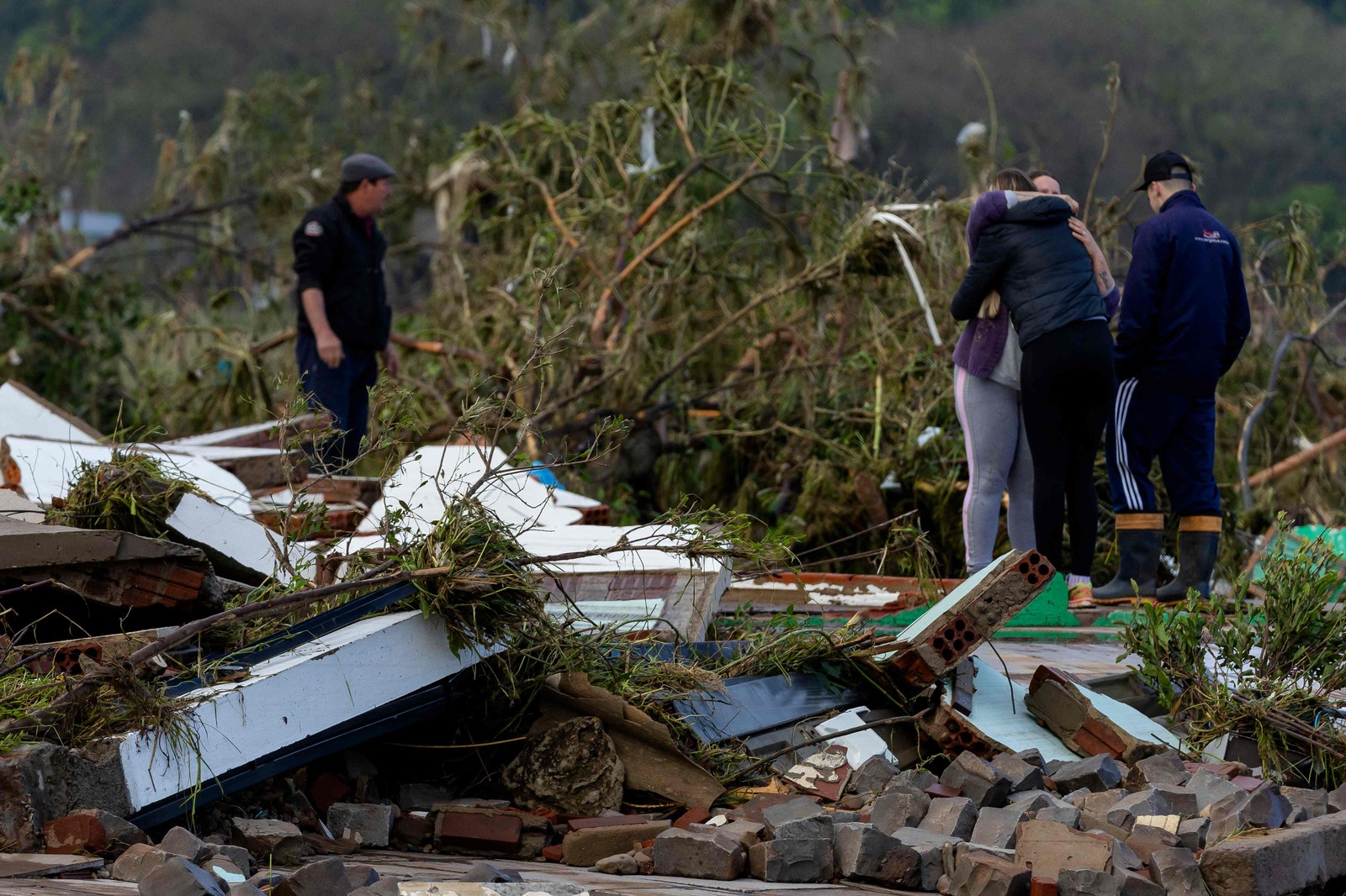 Moradores se abraçam sob os escombros de sua casa após um ciclone em Muçum, Rio Grande do Sul — Foto: SILVIO ÁVILA/AFP