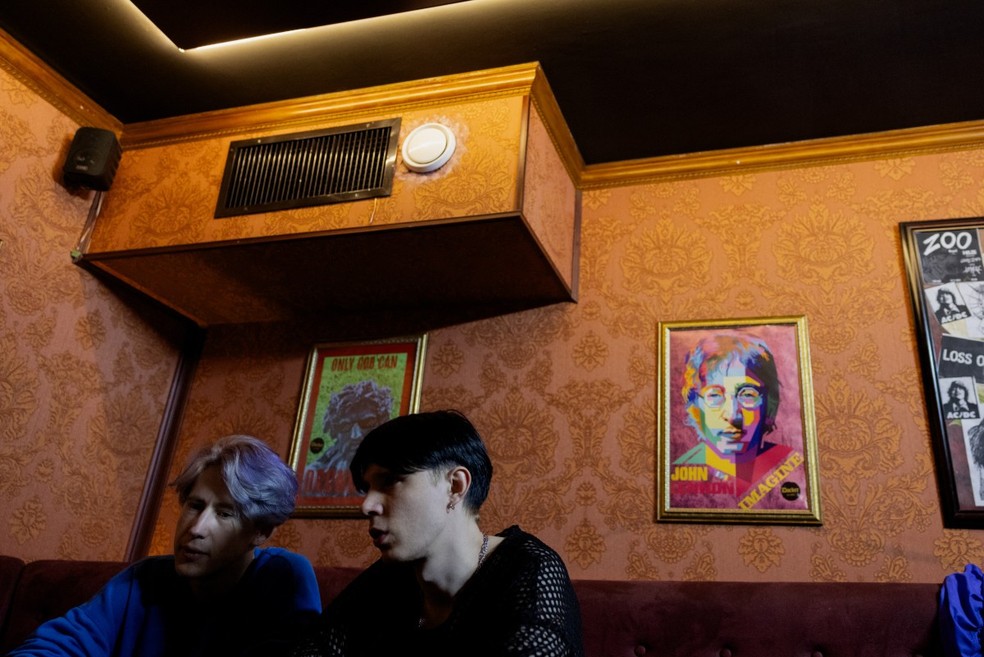 Os membros da banda punk-rock Susidy Sterpliat, o baterista Oleksandr Pavlov e o guitarrista Artur Zubarevof sentam-se no camarim antes do show em um pub em Vinnytsia, em 22 de março de 2025, em meio à invasão russa da Ucrânia — Foto: TETIANA DZHAFAROVA / AFP