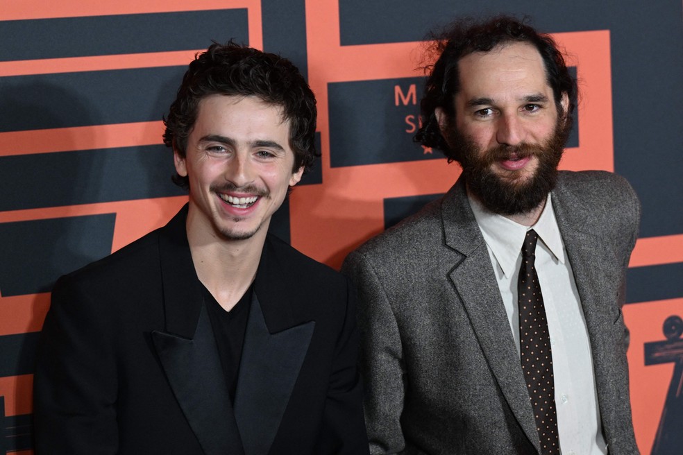 O ator franco-americano Timothée Chalamet (à esquerda) e o diretor de cinema americano Josh Safdie posam para fotos ao chegarem ao tapete vermelho para a exibição de seu filme Marty Supreme em Pequim. — Foto: ADEK BERRY/AFP