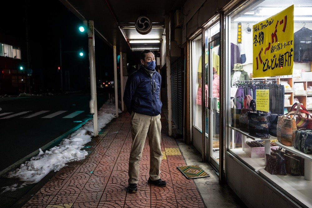 Shinichi Sato do lado de fora de sua loja de roupas, na Ilha Sado, onde sua família vive há dez geraçõesThe New York Times