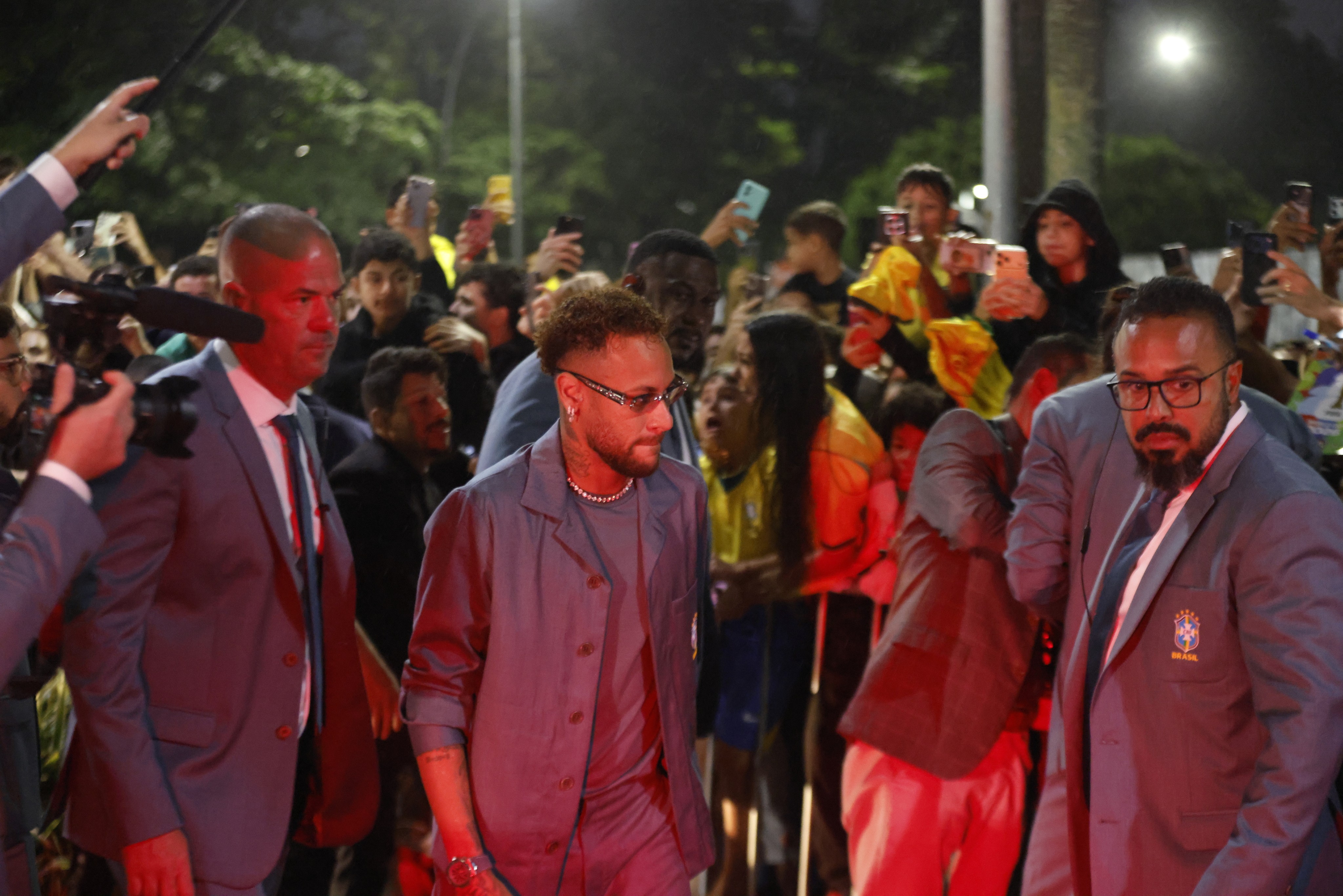 Sob chuva, Neymar e jogadores da seleção brasileira fazem a festa dos torcedores na saída do hotel