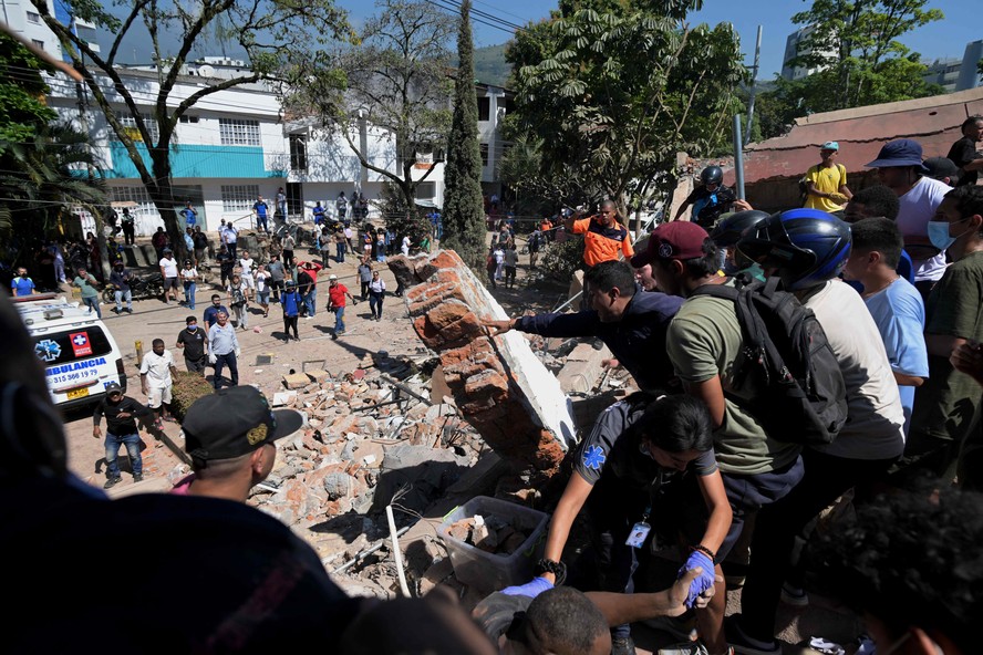 Pessoas trabalham em escombros de prédio em Cali, na Colômbia, após terremoto de magnitude 7.4