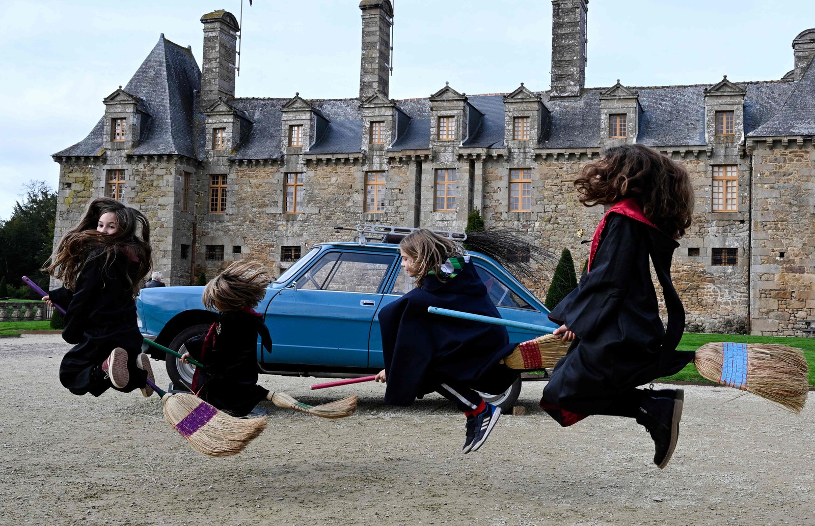 Crianças fingem voar em vassouras na escola de bruxaria do Château Le Rocher-Portail, na Bretanha, França — Foto: Damien Meyer/ AFP