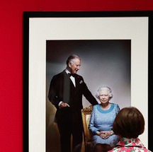 Visitante olha foto da Rainha Elizabeth II com Rei Charles III — Foto: AFP