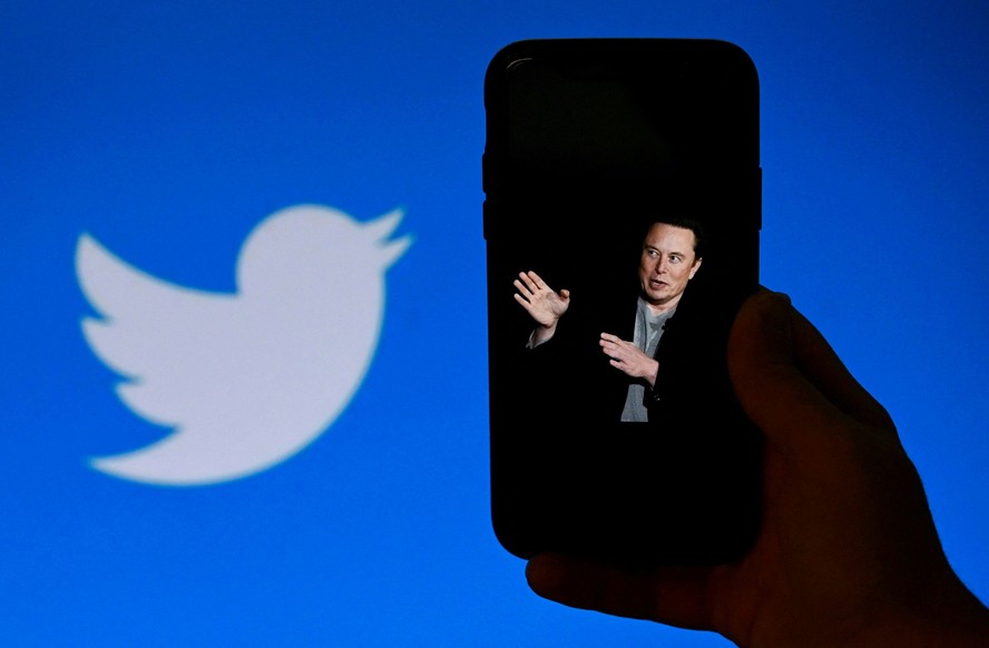 Tela de celular exibe foto de Elon Musk com a logo do Twitter ao fundo