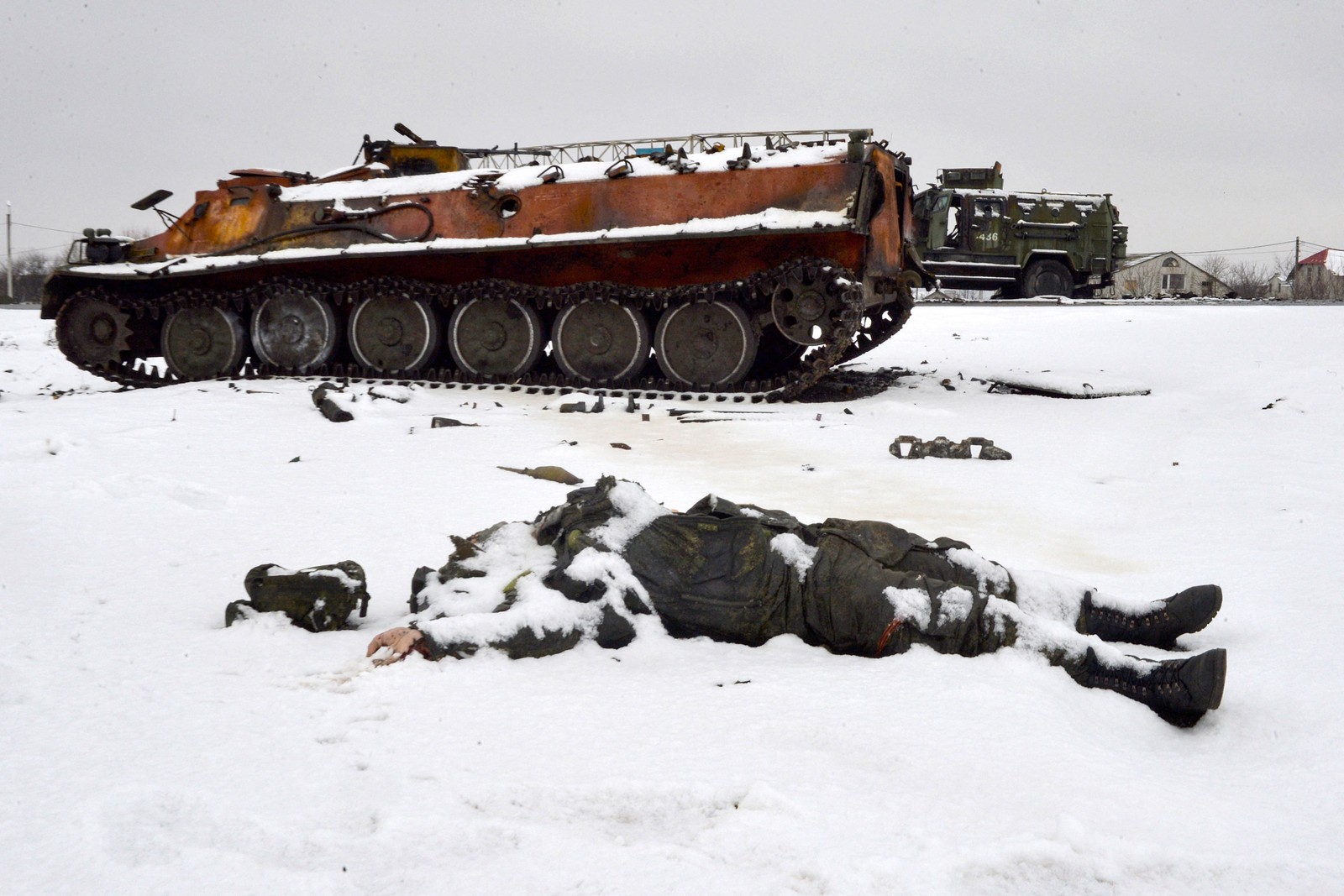 Corpo de um militar russo fica encoberto pela neve, próximo a veículos militares russos destruídos na beira da estrada nos arredores de Kharkiv — Foto: SERGEY BOBOK / AFP