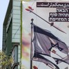 Banner mostrando mísseis e drones voando ao lado de uma bandeira israelense rasgada, com texto em persa 