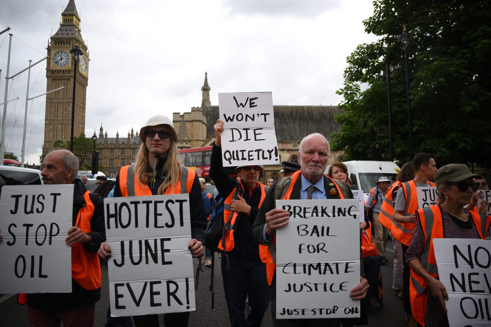 Ativistas climáticos do movimento 'Just Stop Oil' protestam na Praça do Parlamento em Londres, enquanto levantam cartazes como "não morreremos em silêncio" e "junho mais quente de todos os tempos". — Foto: Daniel LEAL/AFP