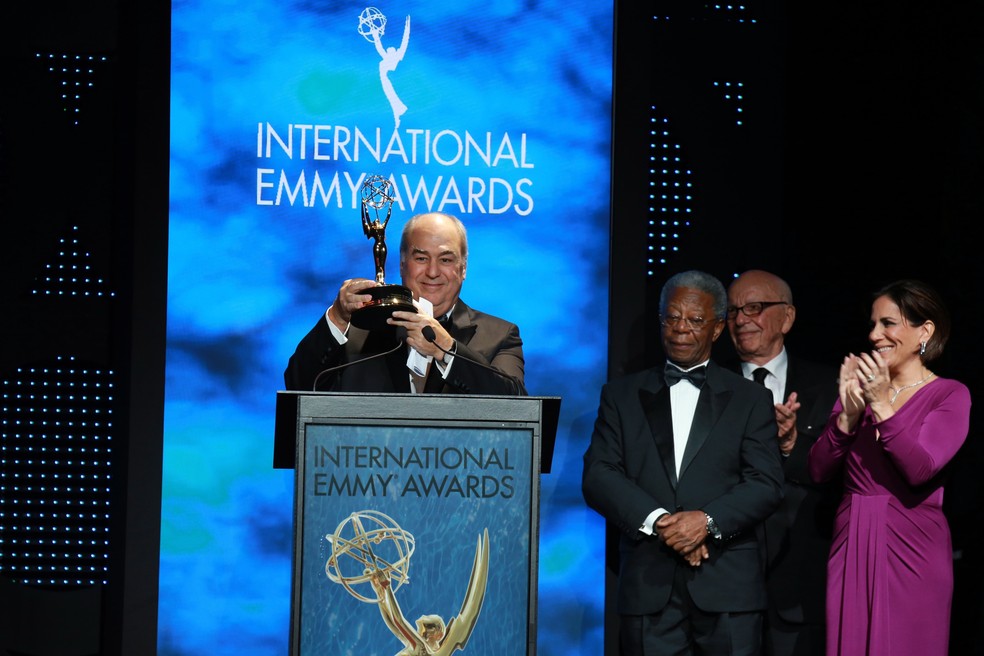 Roberto Irineu Marinho ergue o Emmy Internacional, observado pelos atores Milton Gonçalves e Glória Pires e o empresário de mídia australiano Rupert Murdoch, em 2014 — Foto: Divulgação/TV Globo