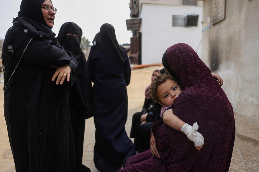 Mãe carrega criança ferida no Hospital al-Shifa, em Gaza