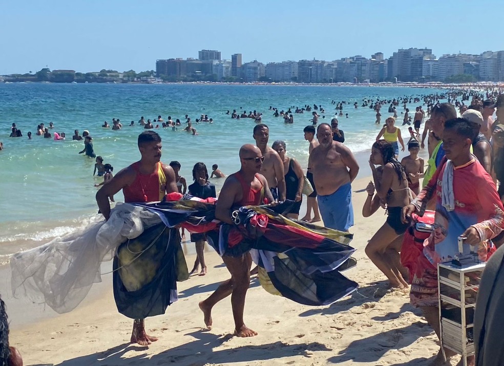 Bombeiros carregam faixa que era puxada por aeronave que caiu em Copacabana — Foto: João Vitor Costa/Agência O Globo