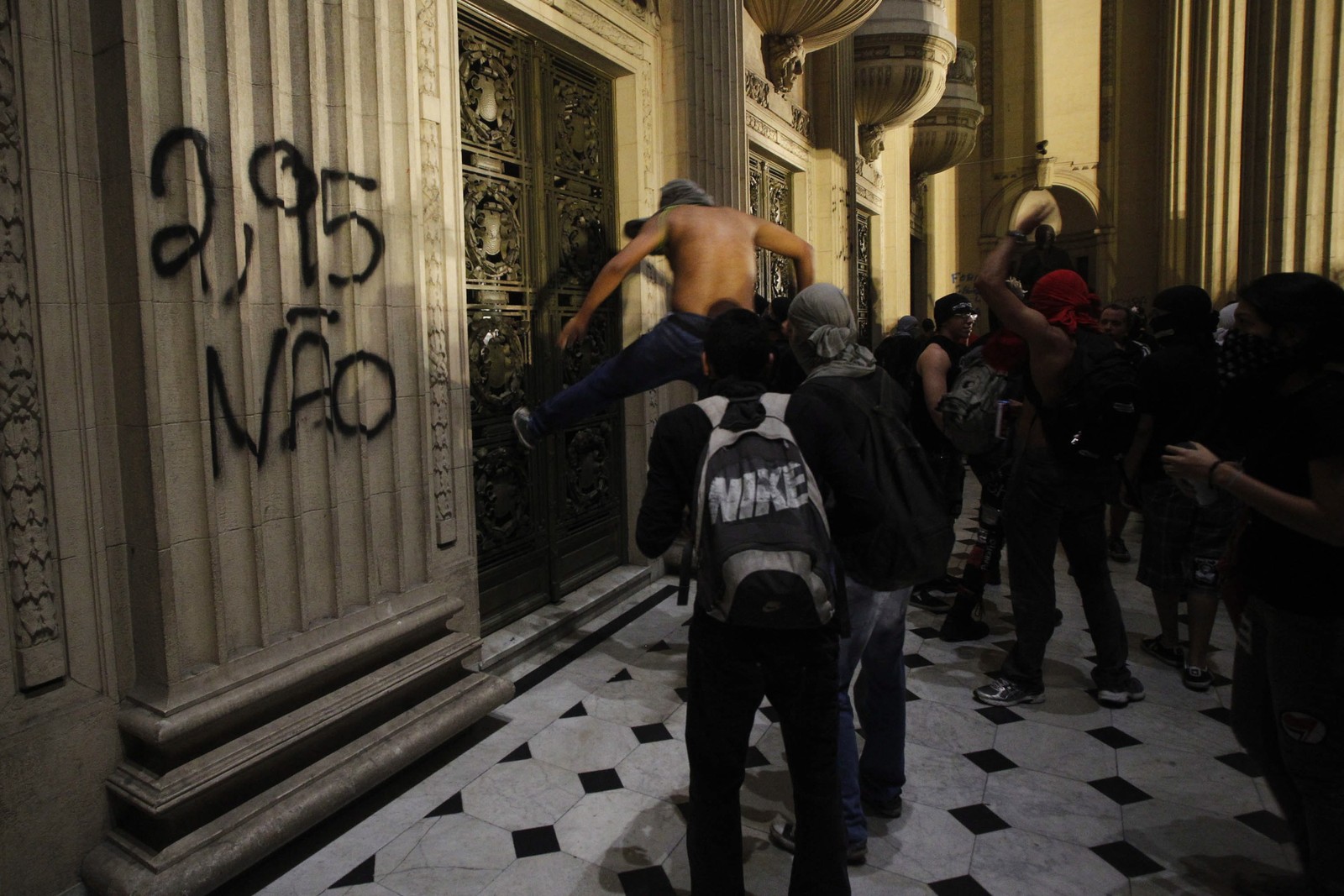 Manifestantes tentam destruir a pontapé um portão do prédio da Assembleia Legislativa do Rio de Janeiro.  — Foto: Pedro Kirilos / Agência O Globo