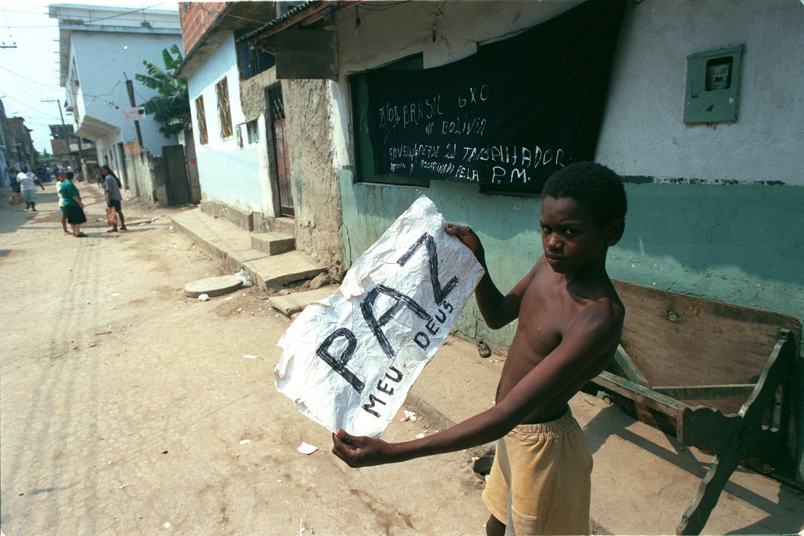 Menino da Favela de Vigário Geral segura um cartaz em que pede paz para a comunidade após a chacina, em 1º de setembro de 1993 — Foto: Celso Meira / Agência O Globo