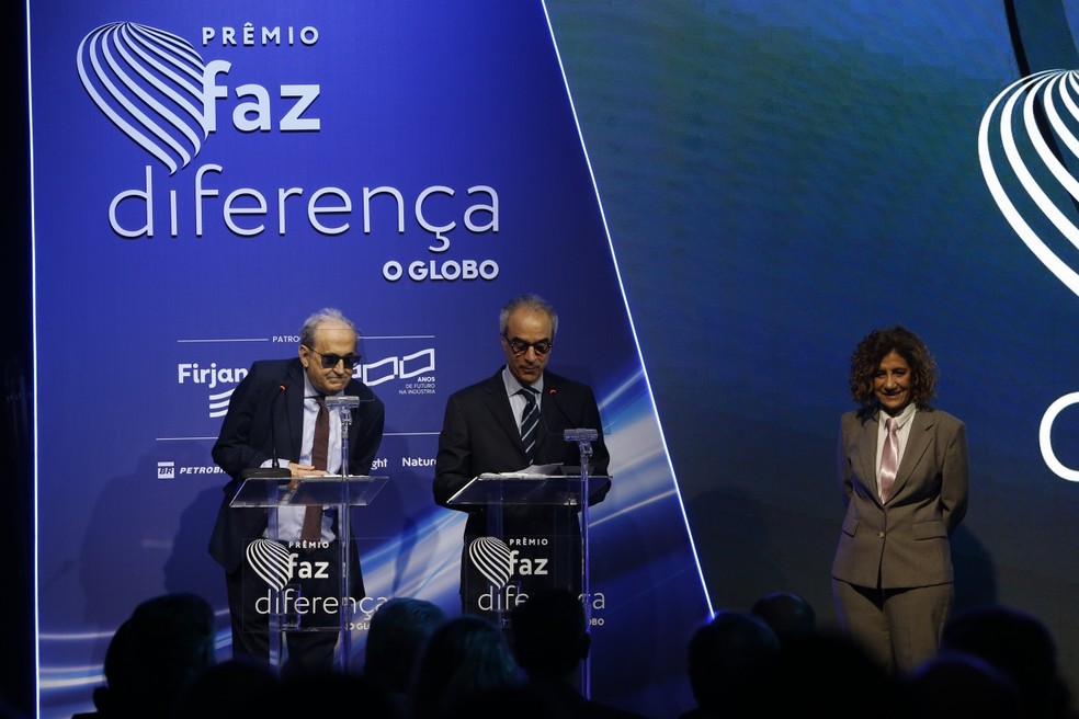 Os colunistas Ancelmo Gois e Miriam Leitão, nas pontas, e o presidente do Conselho de Administração do Grupo Globo, João Roberto Marinho, centralizado, durante a cerimônia do Prêmio Faz Diferença 2025 — Foto: Alexandre Cassiano / Agência O Globo