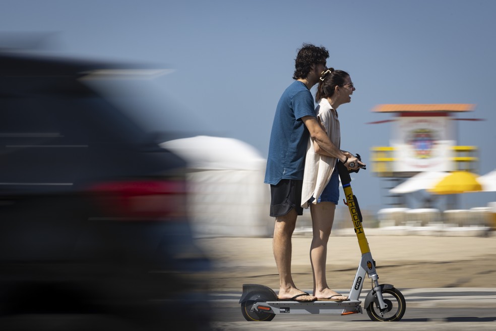 Dupla compartilha a mesma patinete na Zona Sul do Rio — Foto: Márcia Foletto