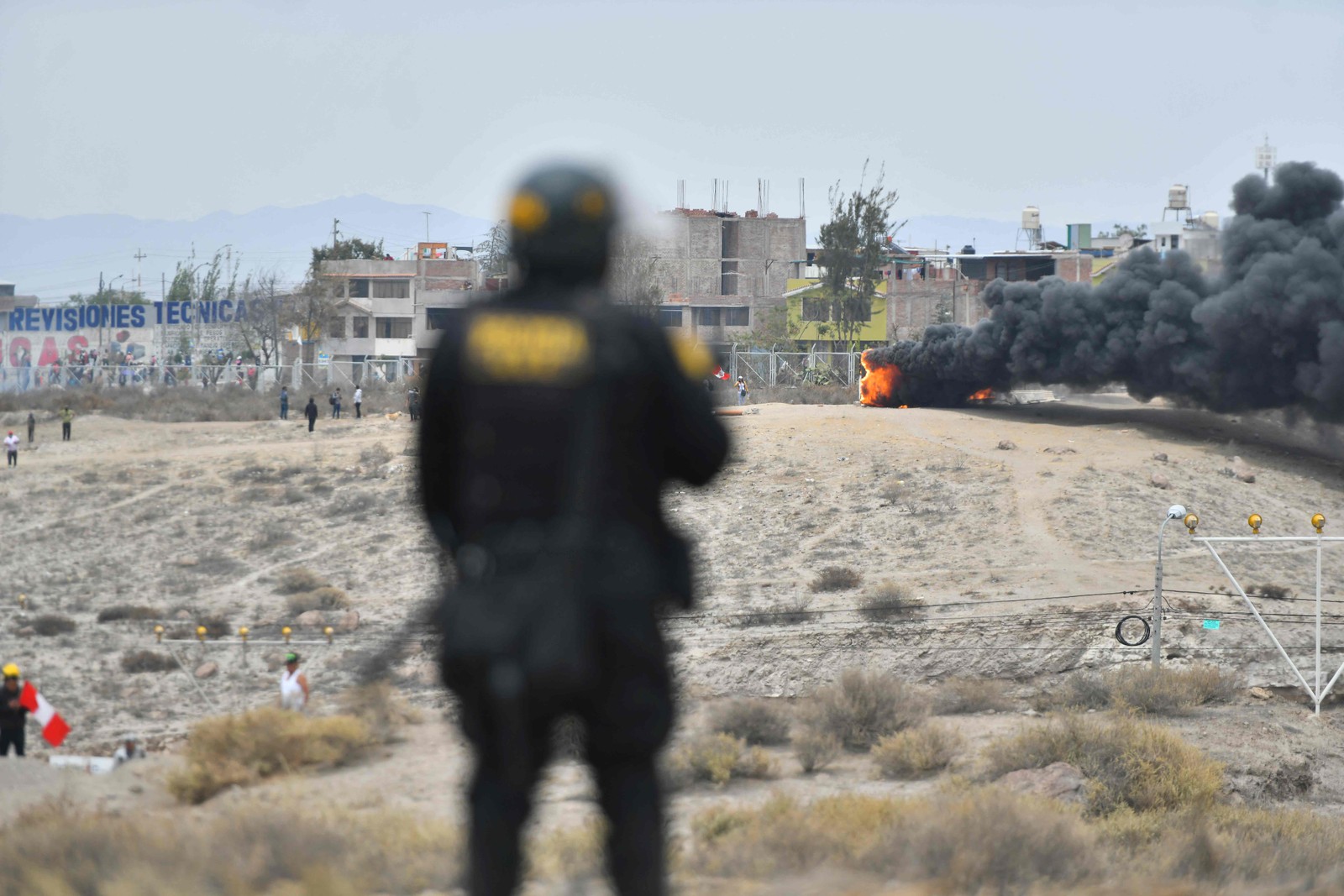 Policial observa incêndio durante manifestação na rodovia pan-americana — Foto: Diego Ramos / AFP