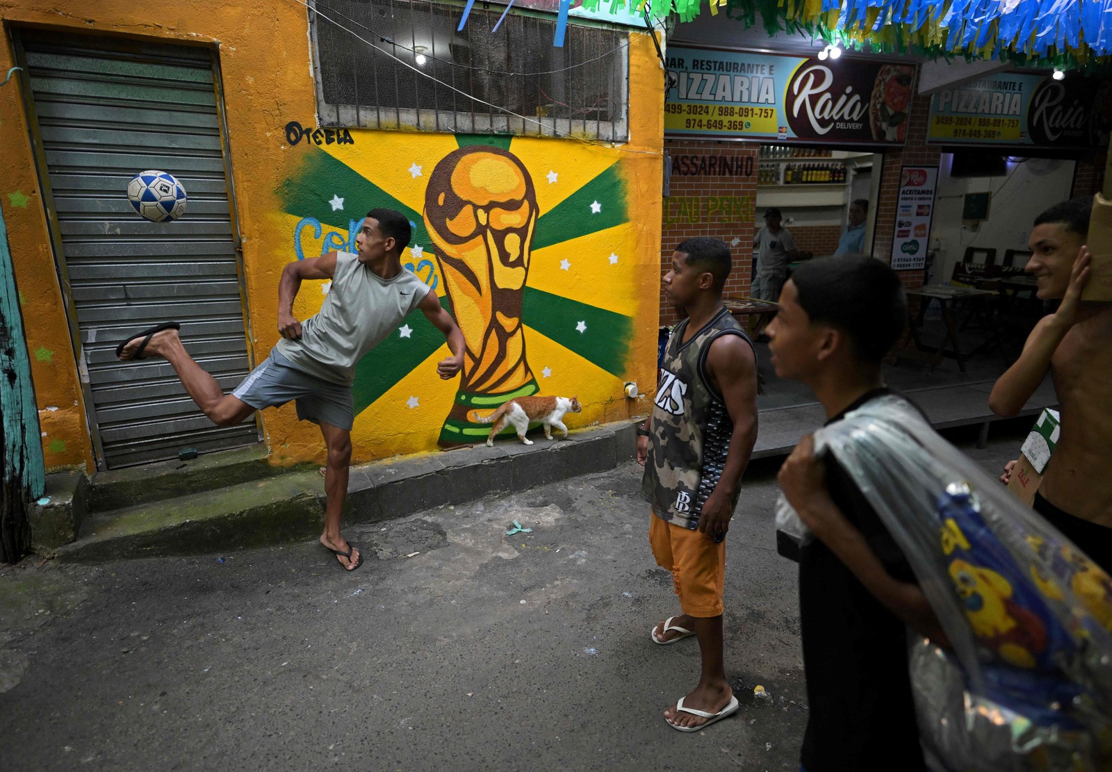 Moradores jogam altinha em rua decorada em razão da Copa, na Rocinha, comunidade da Zona Sul do Rio — Foto: CARL DE SOUZA/AFP