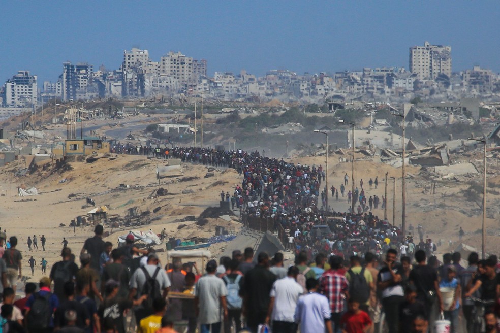 Milhares de palestinos começam a voltar a pé para o norte de Gaza por estrada costeira de al-Rashid, após início do cessar-fogo — Foto: Bashar Taleb/AFP