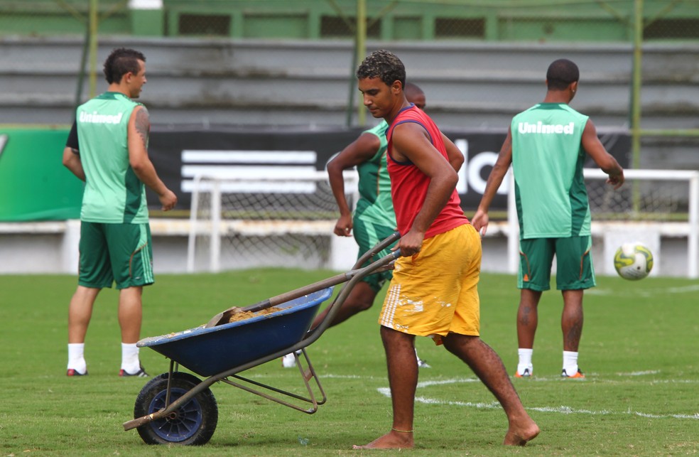 Homem tapa buracos com areia em treino do Fluminense nas Laranjeiras — Foto: Ivo Gonzalez