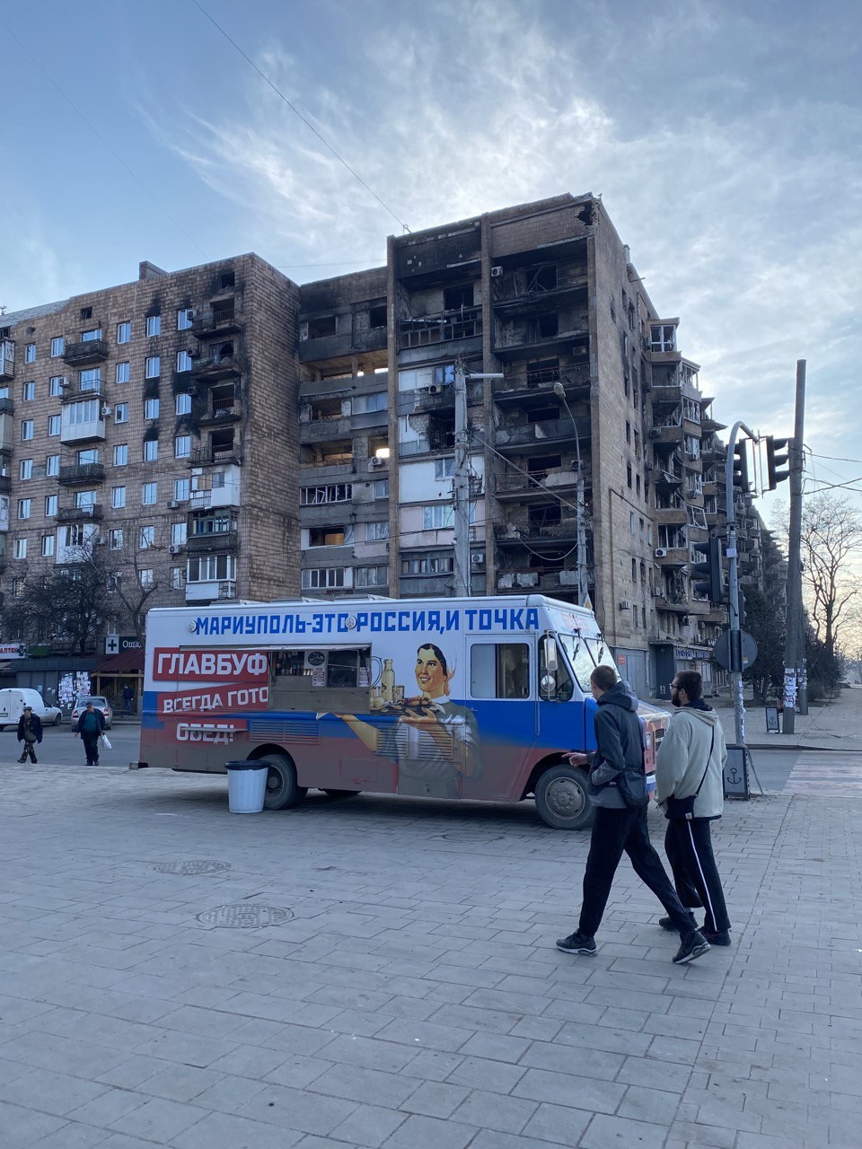 Propaganda russa diz como é grandioso fazer parte da Rússia. Ao fundo, um prédio destruído por bombardeios — Foto: Ekaterina Diachkova/Agência O Globo