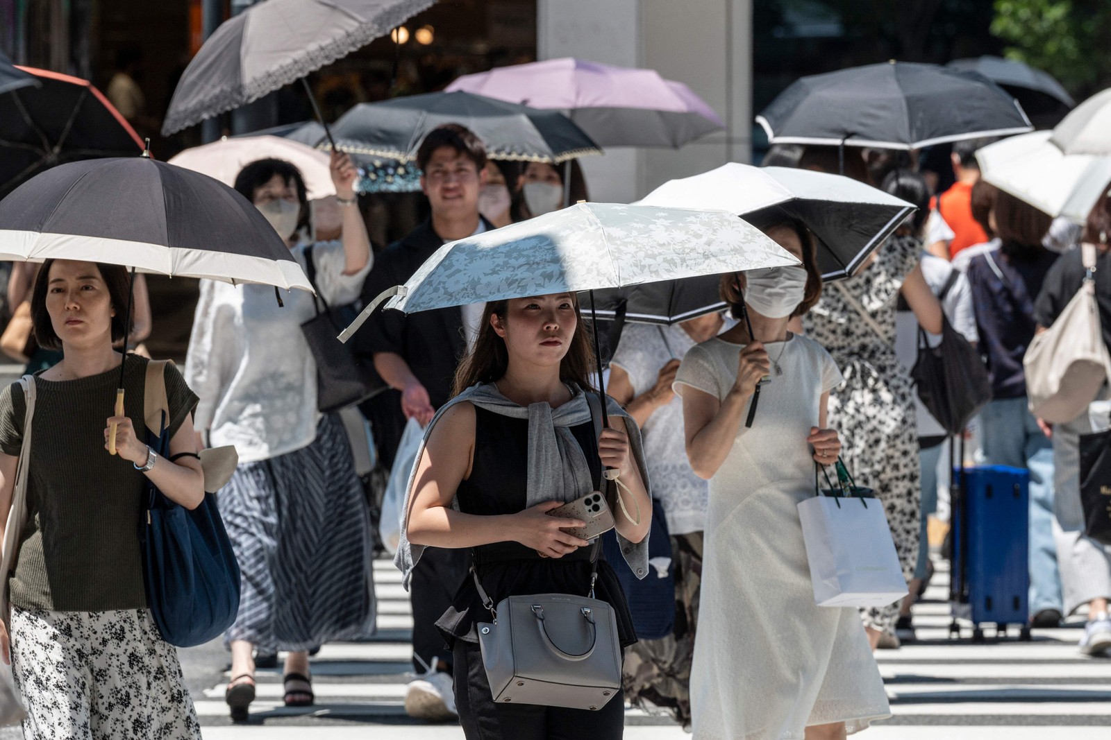 Pedestres atravessam rua no centro de Tóquio. O calor escaldante no Hemisfério Norte ameaçou quebrar recordes e provocar incêndios florestais — Foto: Richard A. Brooks / AFP