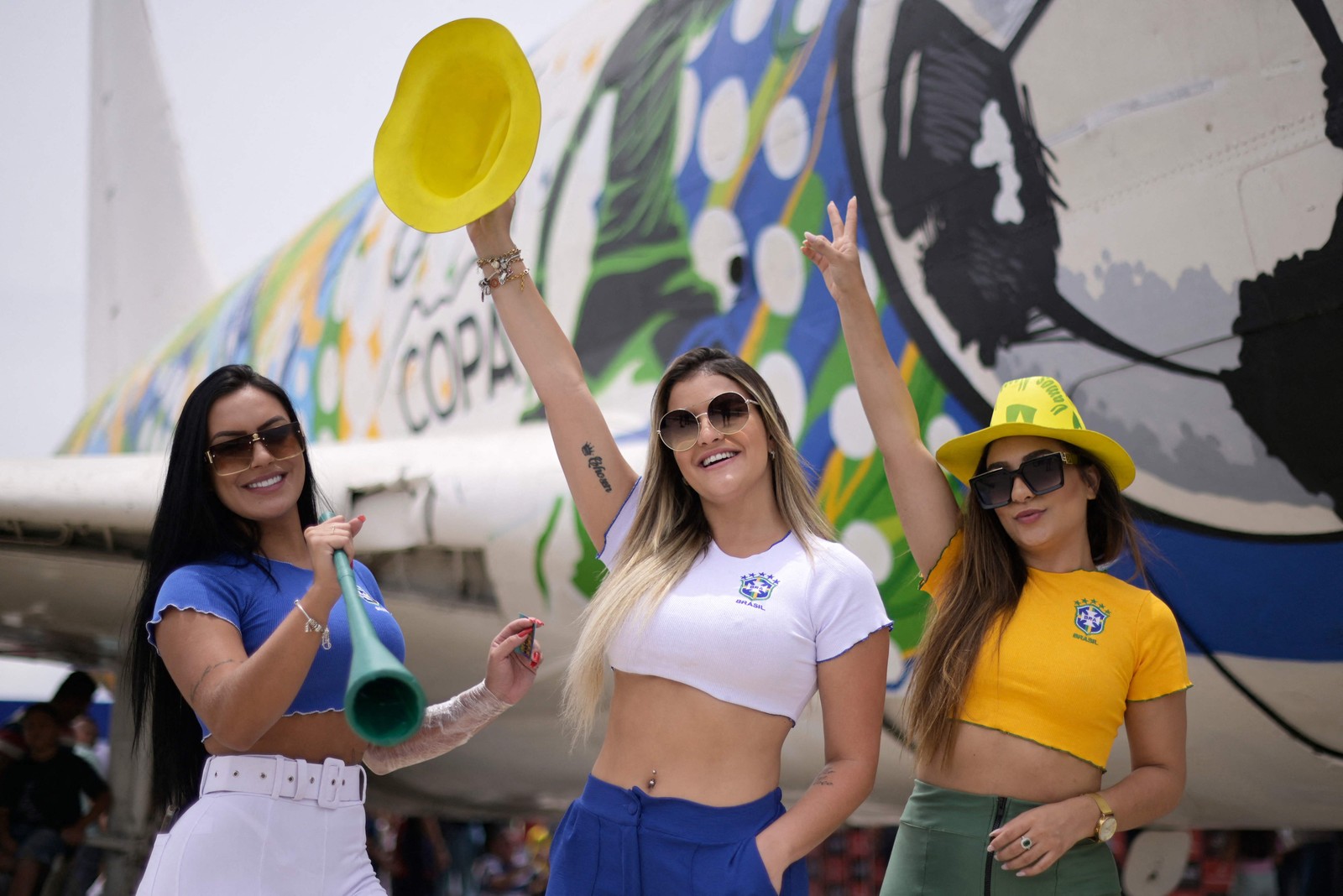 Torcedoras do Brasil posam em frente a um avião abandonado decorado com temas da seleção brasileira em um shopping em Contagem, Minas Gerais — Foto: DOUGLAS MAGNO / AFP