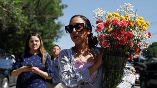 Leti Gomez chega à escola primária Robb com flores, um dia depois de um atirador matar 19 crianças e dois professores na escola em Uvalde, Texas, EUA — Foto: MARCO BELLO / REUTERS