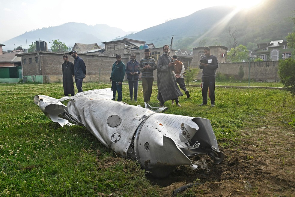 Moradores observam parte danificada de uma aeronave em Wuyan, perto de Srinagar, na Caxemira — Foto: Tauseef MUSTAFA / AFP