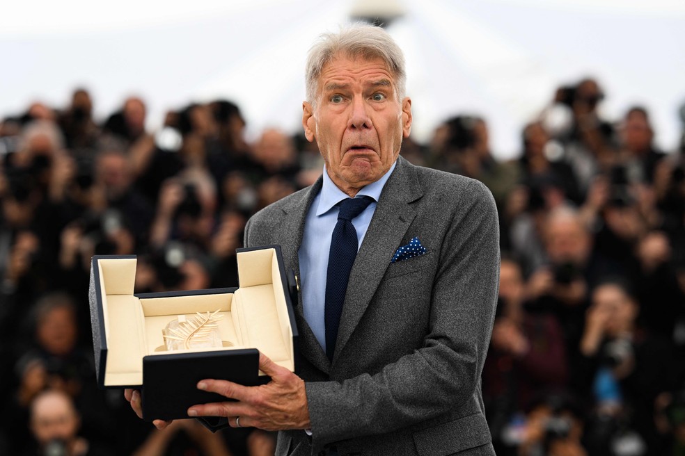 Harrison Ford brinca com sua Palma de Ouro honorária, em Cannes — Foto: Patricia DE MELO MOREIRA / AFP)
